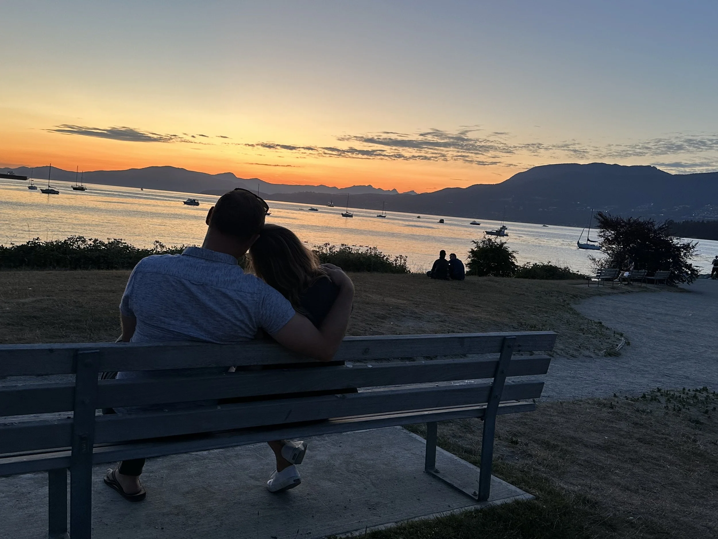 Joe and Kaitlyn on a park bench, watching the sun set over the water
